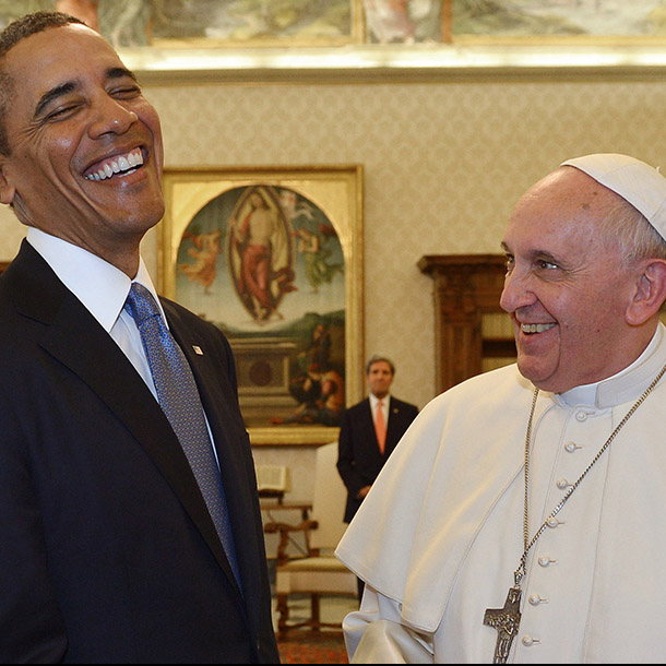 Two men, one in a suit, one in papal attire, smiling together.