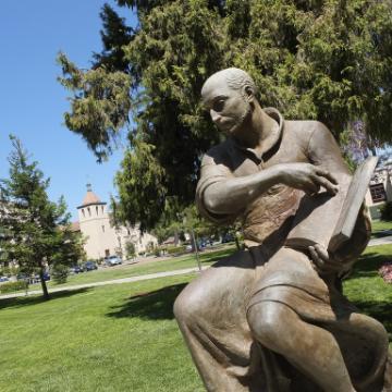 Bronze statue of a seated figure in a park.