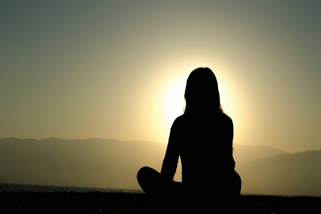 Shadow of a person sitting in front of a sunset 