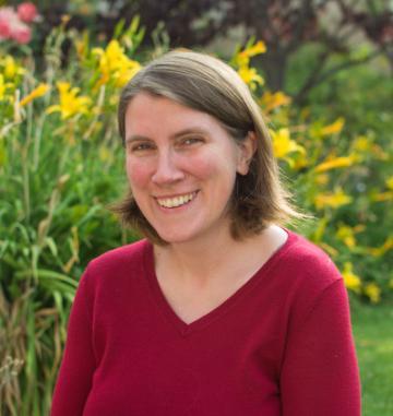 A person in a red shirt with flowers in the background.