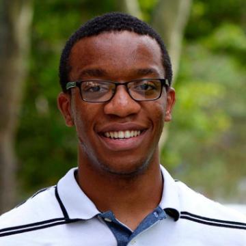 A person wearing glasses and a white collared shirt outdoors.