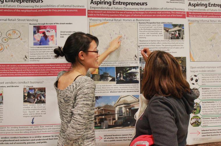 Two women discussing a wall display titled 