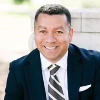 Man in a suit with a striped tie, smiling.