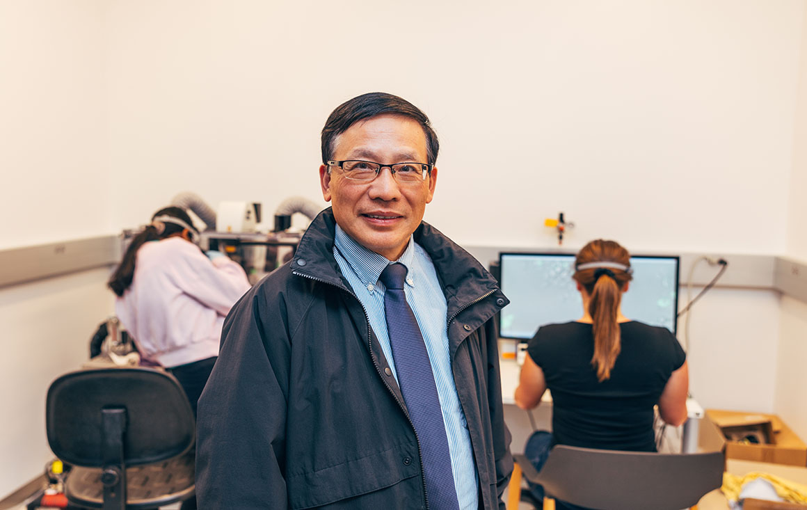 professor smiles as students work behind him