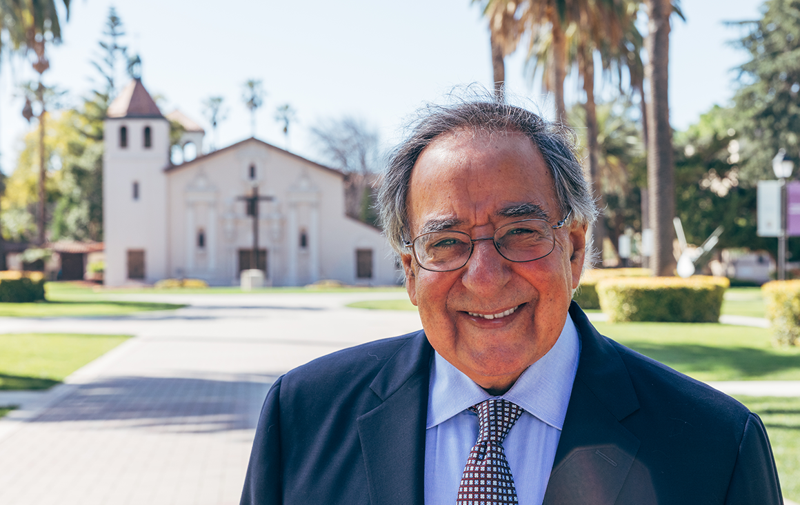 An older man smiles, the Mission Church in the background.