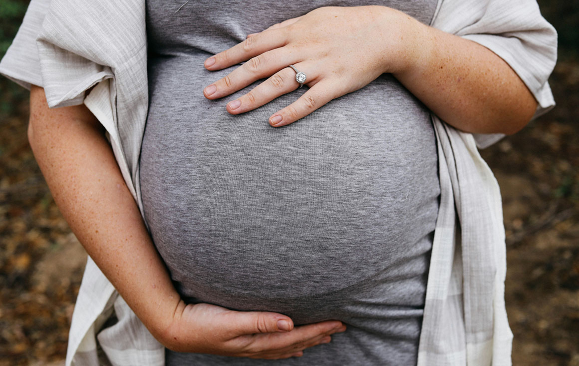 A pregnant person holds their stomach.