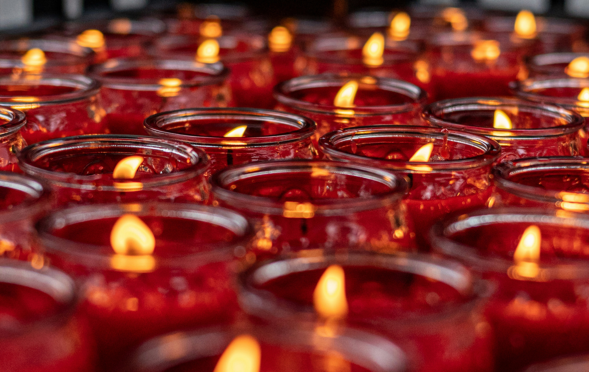 Dozens of church-style red candles positioned next to each other.