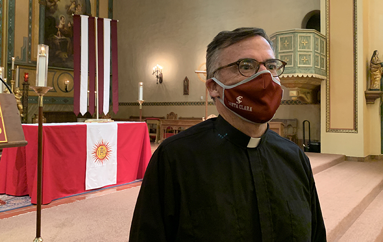 Person wearing a red mask standing in a church with a Canadian flag.