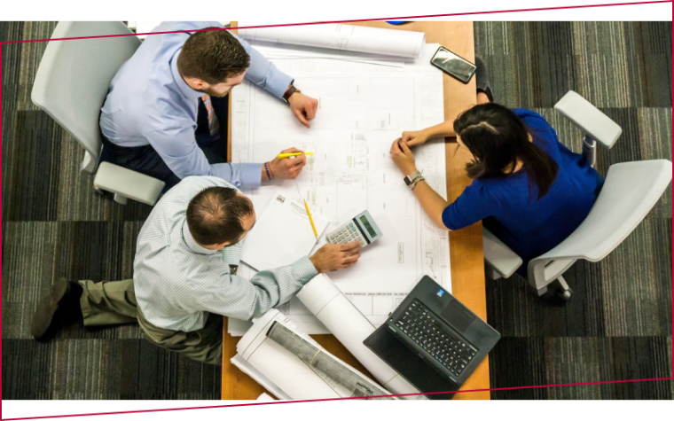 picture of three people sitting at a table and working on a project