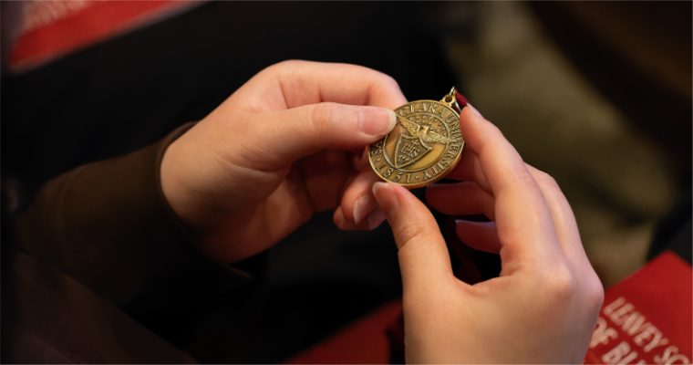Leavey student holding a Santa Clara University medal after receiving award