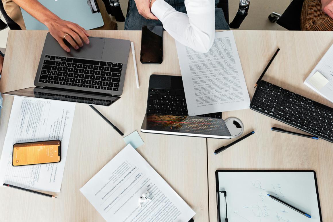 Papers, pens, and laptops spread across a conference room table