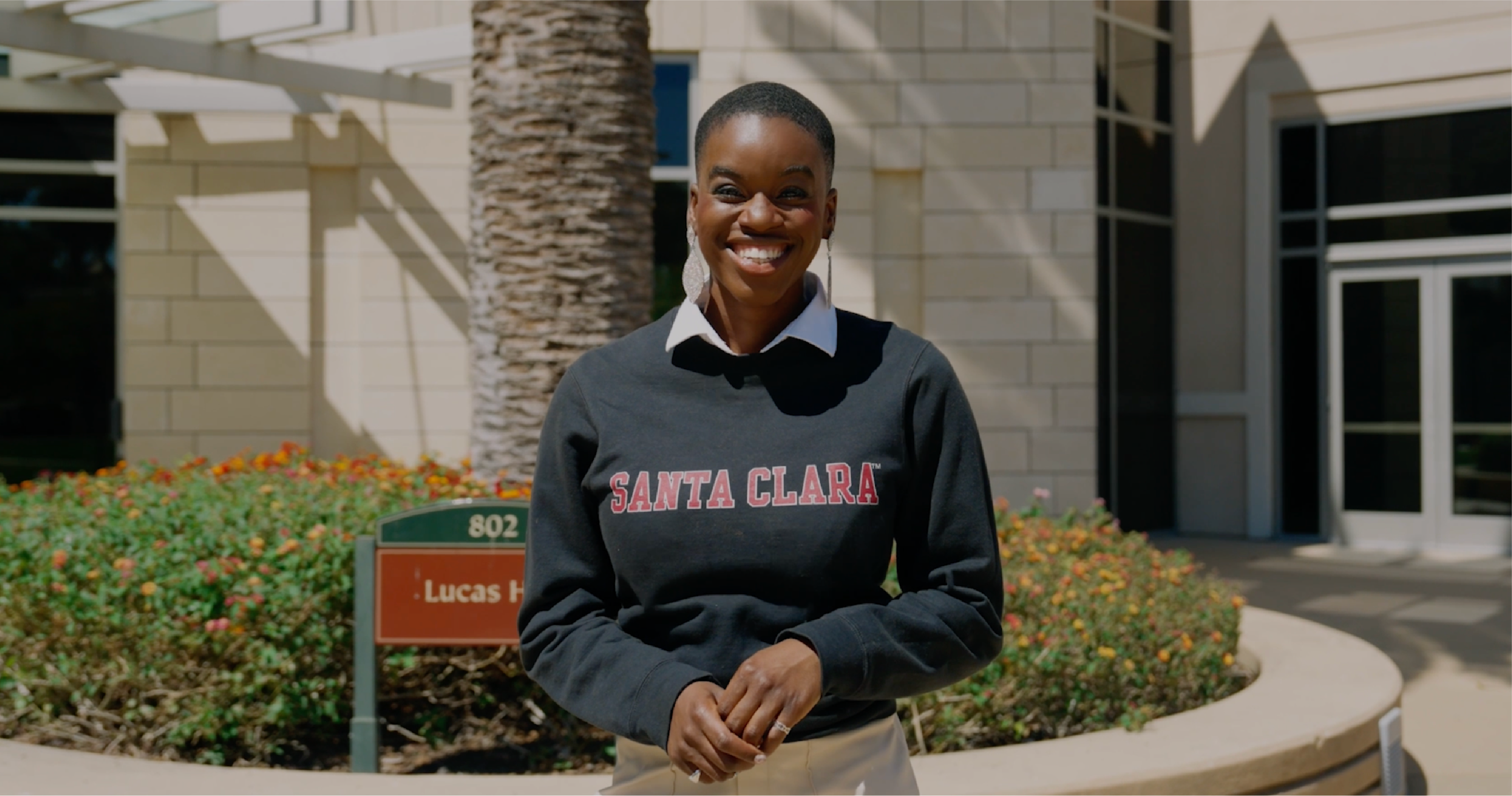 Leavey MS in Marketing alumnae Joy Ofodu wearing a Santa Clara University sweatshirt in front of Lucas Hall