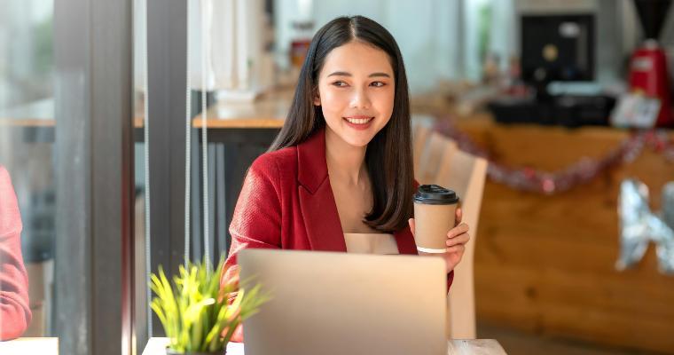 Happy smile young businesswoman in a red suit sitting holding coffee with laptop computer in café image link to article