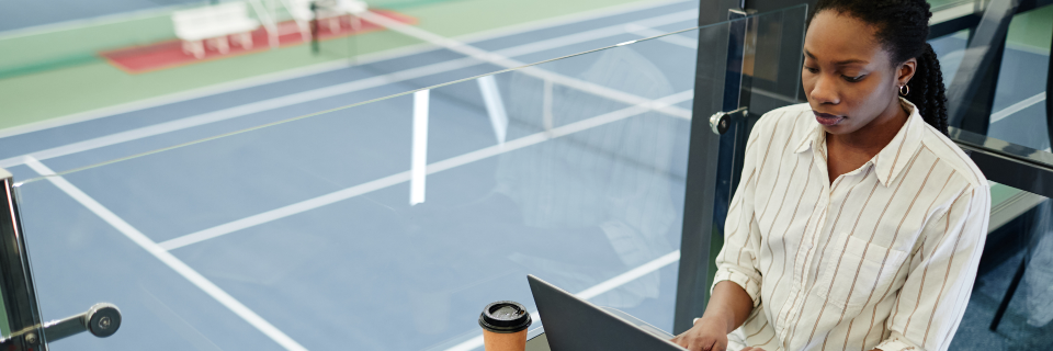 Business professional working on laptop with tennis courts in the background