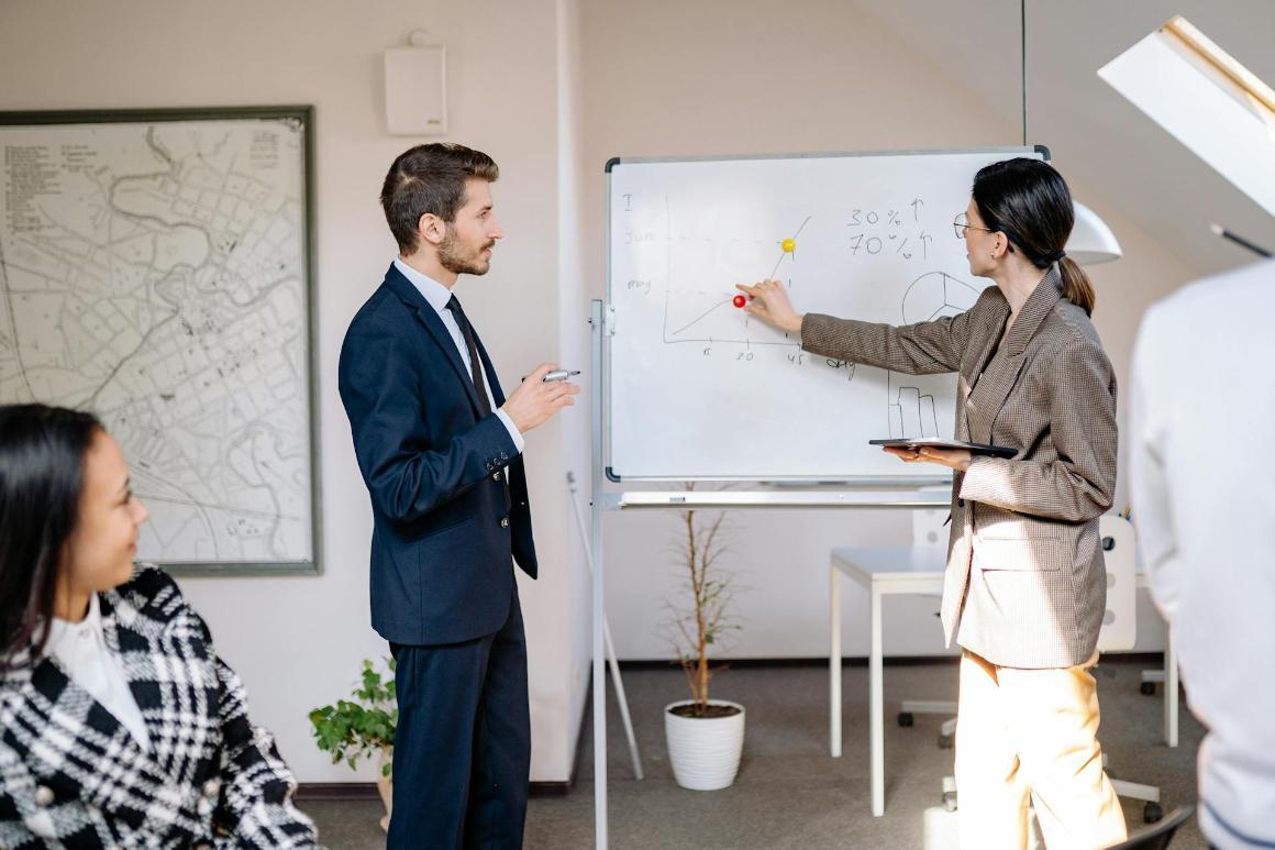 Business team collaborating during an office presentation, using a whiteboard for data analysis and planning