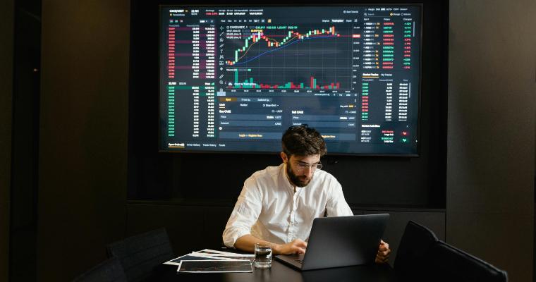 Economist working on laptop with graphs in background image link to article