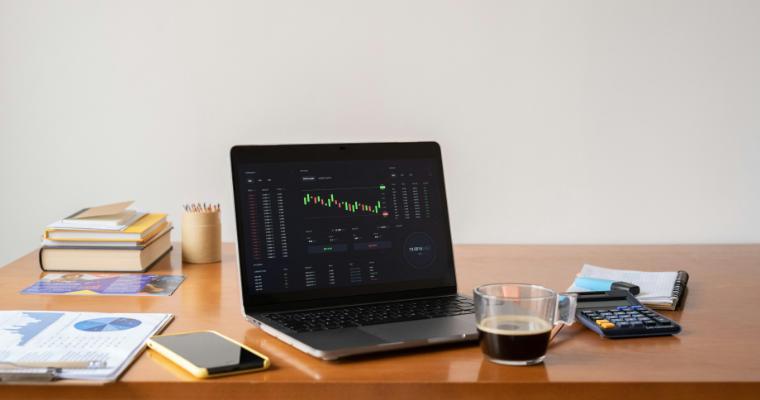 Laptop open on desk displaying stock and financial dashboard