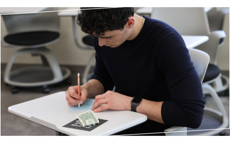 First year Leavey student writing at classroom desk