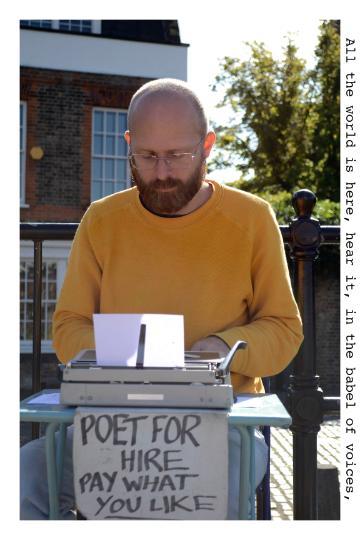 Person in yellow shirt reading from a notebook at a table outside.