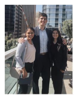 Three people posing together outside with high-rise buildings in the background.