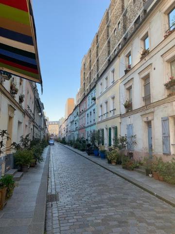 A narrow cobblestone street between old buildings under a clear sky.