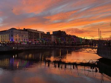 Sunset over a cityscape with reflected colors in the river.