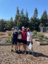 Four people standing outside in a garden area.