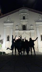 Group of people posing in front of a lit-up building at night.