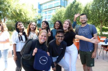 Group of people smiling outdoors in a sunny setting.