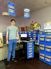 A person standing next to a computer in a decorated office.