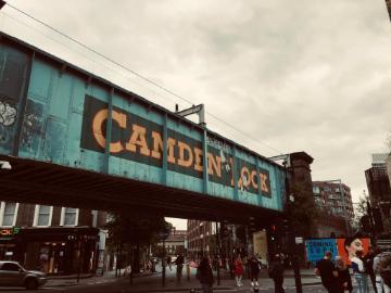 A street scene with a bridge displaying the 'CAMDEN LOCK' sign.