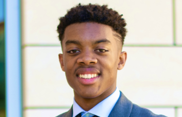 A man in a suit smiling at the camera.