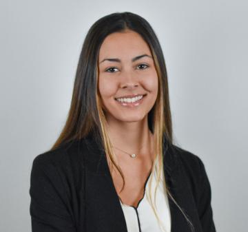 A person in a professional headshot wearing a black blazer and white shirt.