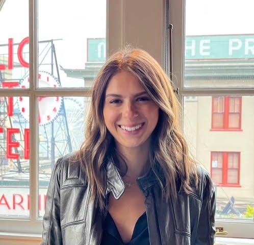 A woman smiling in front of a window.