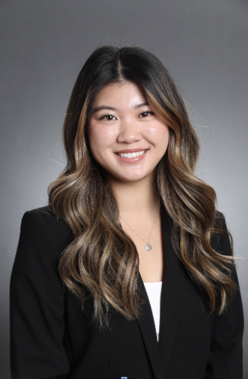 A person smiling in business attire with a gray background.