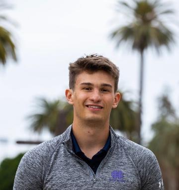 A person outdoors with palm trees in the background.