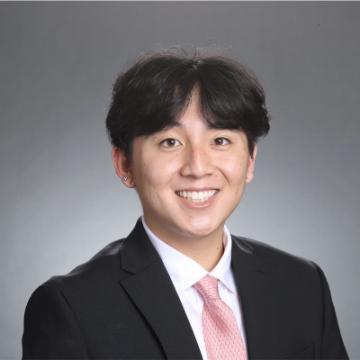 Person wearing a suit and tie, smiling for a professional headshot.