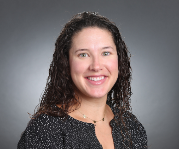 A smiling person named Jenny against a gray background.