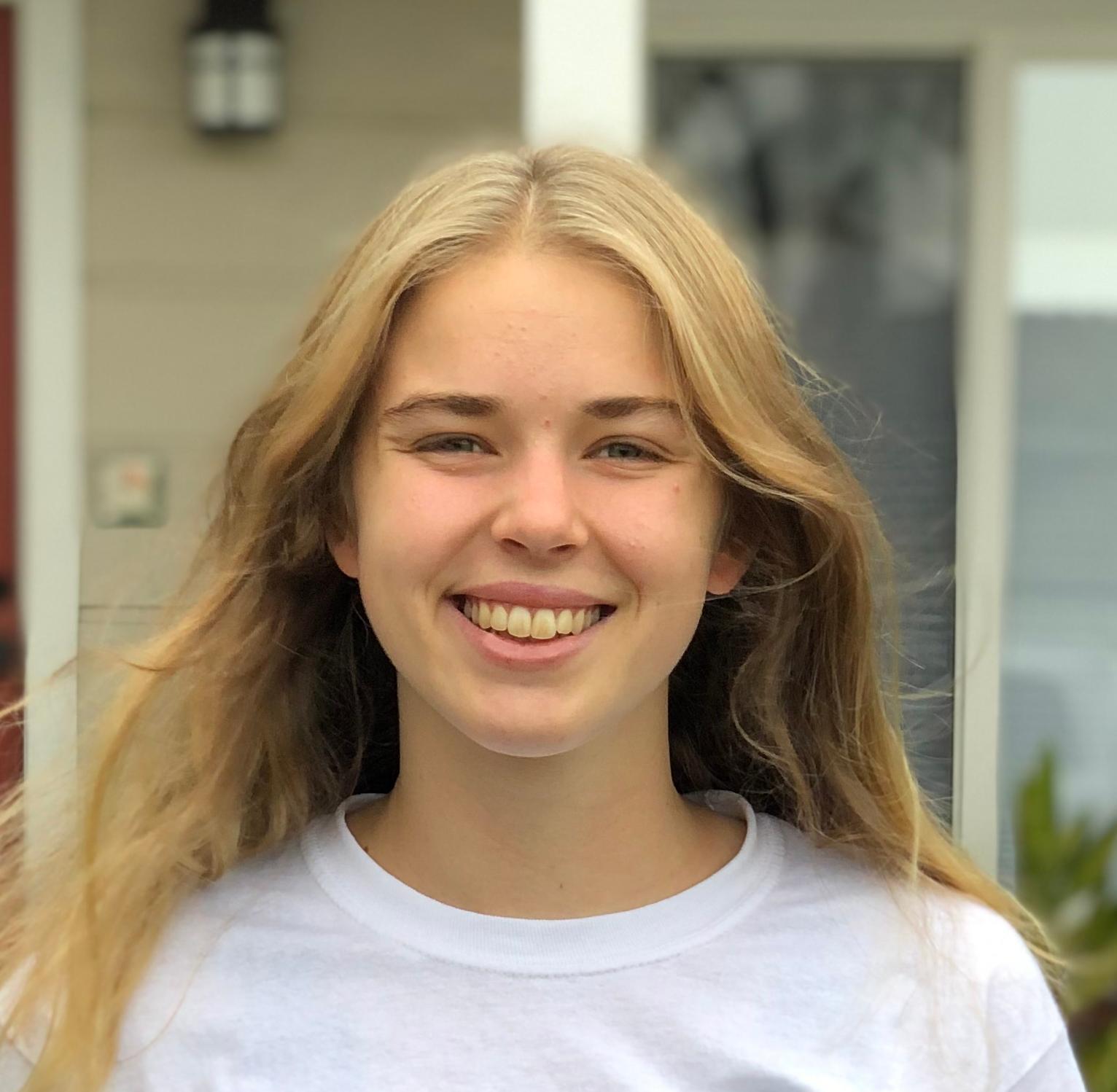 Individual standing outside a building, wearing a white 