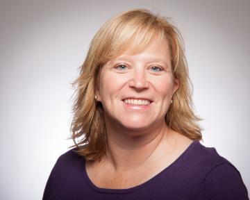 A woman smiling in a studio headshot.