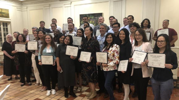 A smiling group of people in business casual dress, holding certificates.