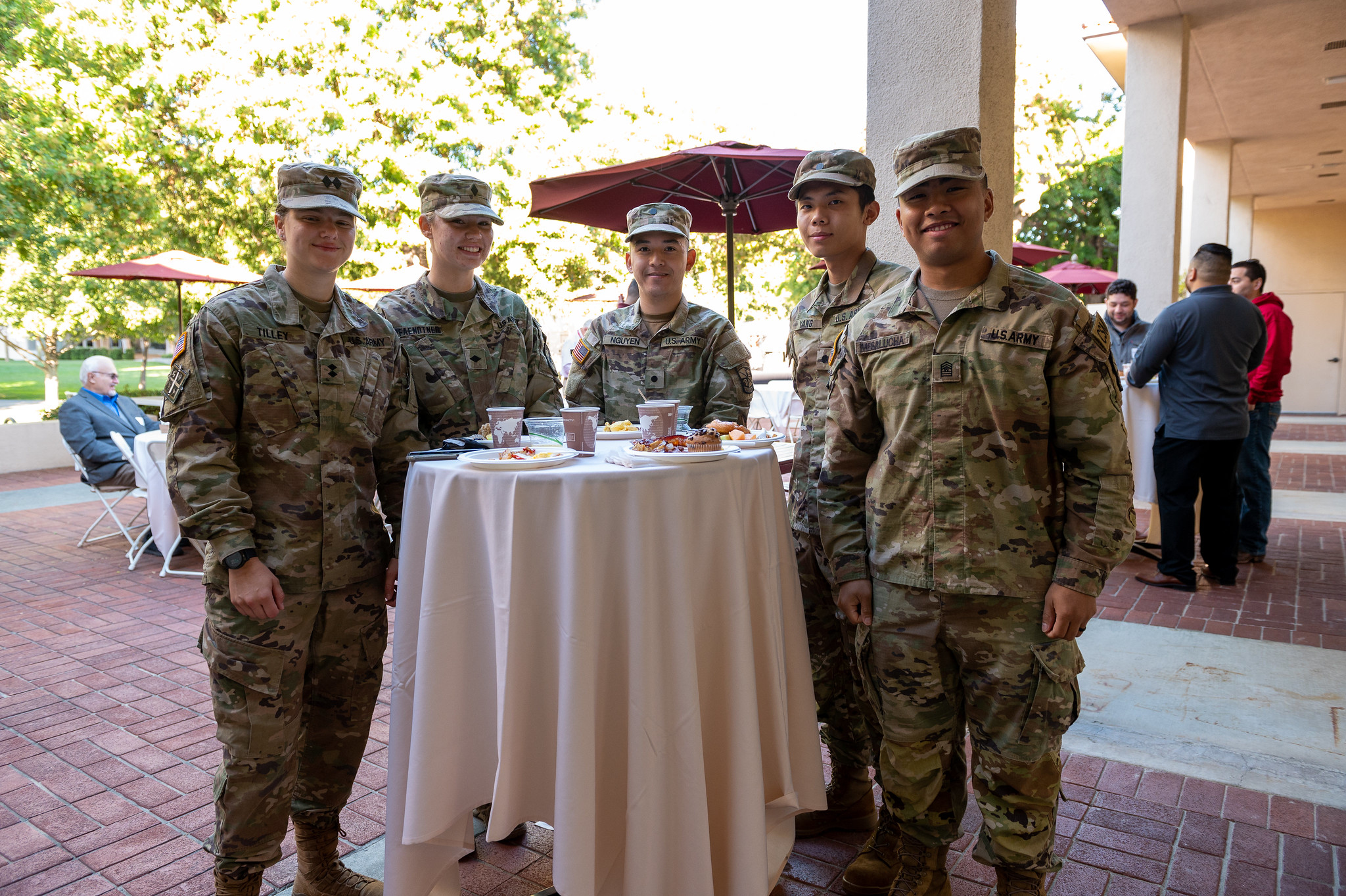 Military personnel standing around a table at an outdoor event.