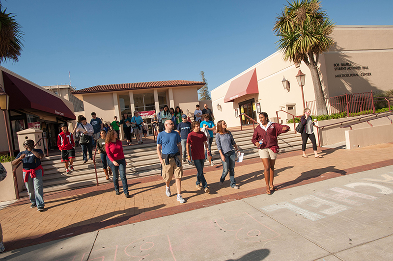 People walking outside a building during an event on a sunny day. 