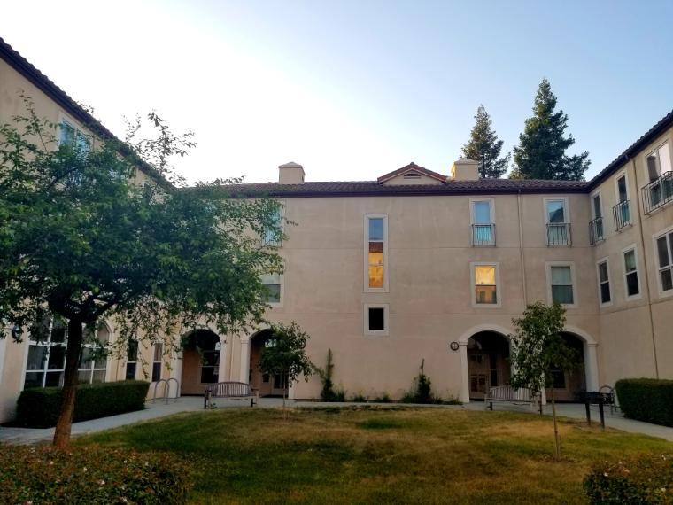 Alt text: Two-story building with arches, trees, and a lawn courtyard.