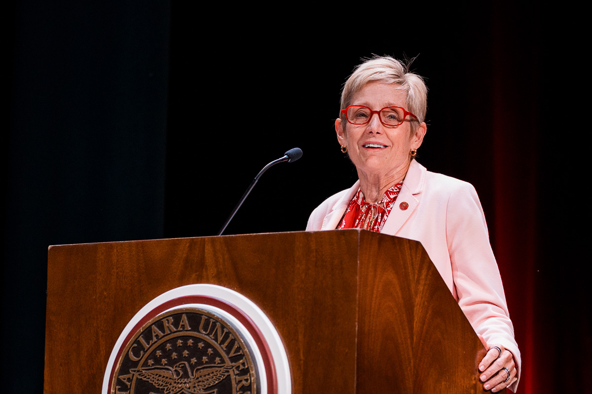 Santa Clara University President Julie Sullivan smiles while speaking at a podium during convocation