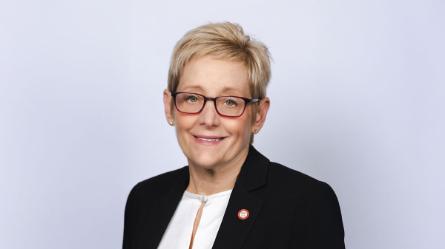 Head Shot of smiling woman with short blond hair and red glasses