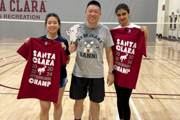 Picture shows three IM Badminton champs smiling in front of the courts with their  tee shirts.