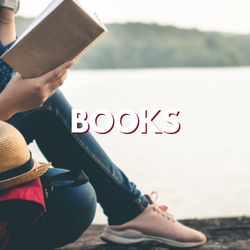 Person reading a book outdoors with the word 