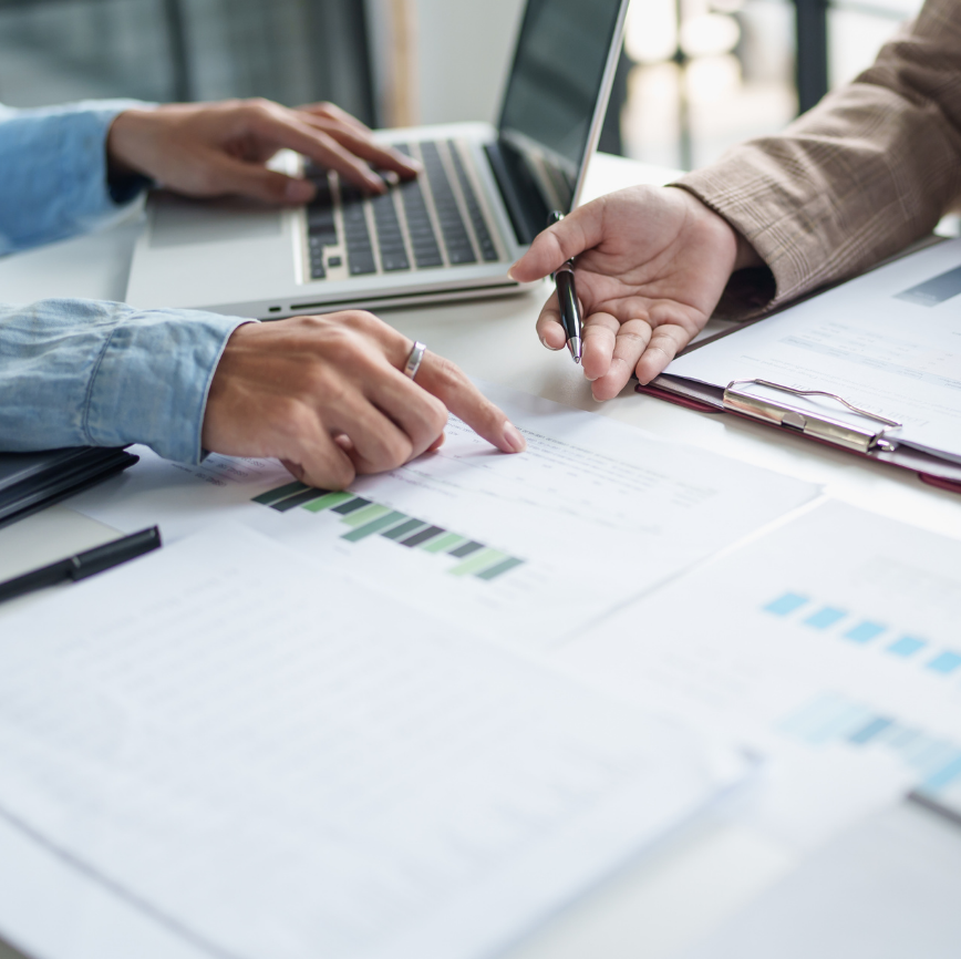 Two individuals pointing at papers on an organized desk. Links to Business Sustainability MBA Concentration page.