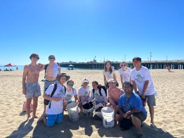 Students on the beach holding buckets and bags of trash in Santa Cruz